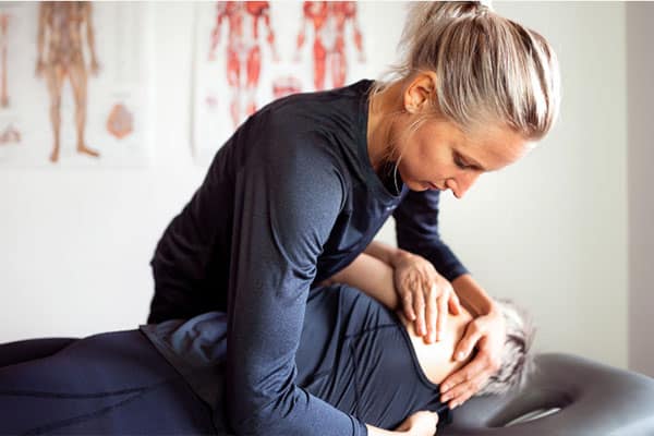 kiropraktor girl in black shirt helping another person with strecthing