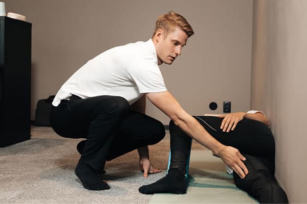 postural guy in white shirt helping another person with strecthing